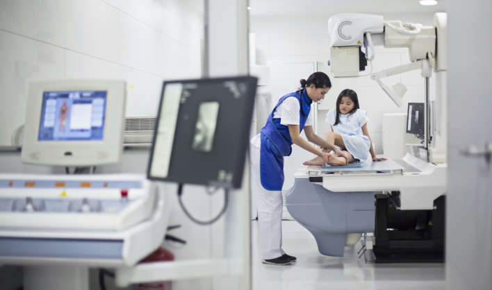 Girl having her leg scanned by an x-ray medical device.